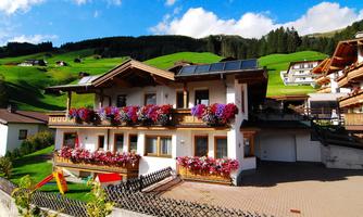 A charming house with colorful flower balconies in a green environment. The picturesque landscape and the blue sky give the image a cozy atmosphere.