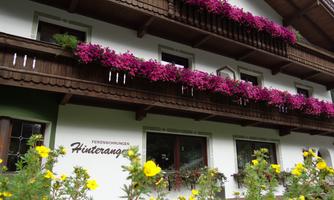 A charming holiday home with blooming plants on the balconies. Colorful flowerbeds stretch out in front of the facade.