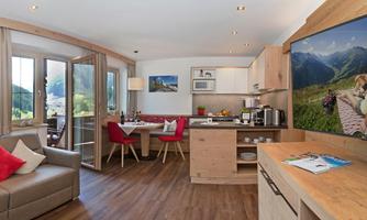 A modern kitchen-living room with lots of wood and large windows. The space is bright and inviting, ideal for relaxing hours.