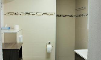 A modern bathroom with neutral tiles and a bright design. There is a shower, a sink, and a comfortable toilet area.