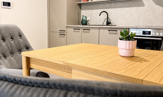 A modern kitchen with a wood-colored table and cozy chairs. On the table, there is a small plant pot.