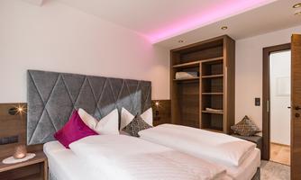 A modern bedroom with two single beds and stylish cushions. The walls are light, and soft lighting creates a pleasant atmosphere.