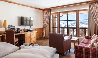 A cozy room with modern design and wood details. Large windows offer a view of the snowy mountains outside.