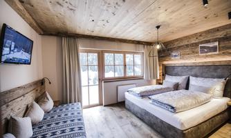 A comfortable bedroom with wood paneling and two beds. Large windows offer a view of the snowy landscape.