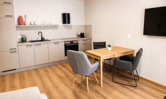A modern kitchen with a dining area and stylish chairs. The room feels bright and inviting.