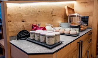 A buffet with various glasses containing dairy products. In the background, dishes and a container for breakfast ingredients can be seen.