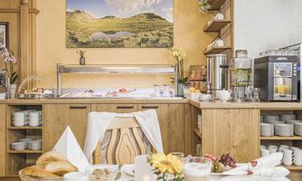 An inviting breakfast buffet in a cozy restaurant. The table is set with various dishes and drinks, surrounded by warm wooden shelves.