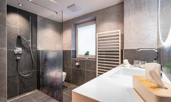 A modern bathroom with a large shower and elegant tiles. The room has plenty of light from the window and a stylish washbasin installation.