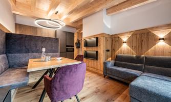 Modern, cozy living space with wooden ceiling and stylish furniture. A dining table with a jug of water and comfortable seating invites you to linger.