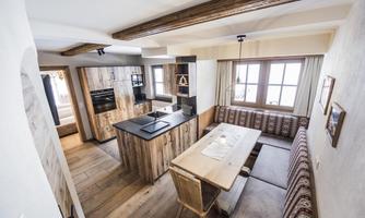 A modern kitchen with wooden furniture and a large table.  
Plenty of daylight streams through the windows, creating an inviting atmosphere.