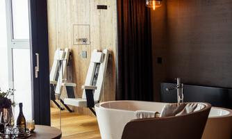 A modern bathroom with a freestanding bathtub and stylish seating options. The wood and color combination creates a warm, inviting atmosphere.