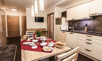 A modern kitchen with a wooden dining area and a set table. The room is bright and inviting, ideal for shared meals.