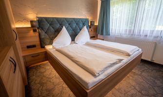 A cozy bedroom with a double bed and elegant bedding. The windows let in plenty of daylight and the walls are stylishly designed.
