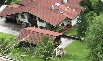 A cozy house with a red gable roof and a well-maintained garden. Surrounded by green trees and a quiet environment.