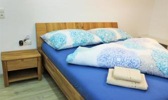 A cozy bedroom with a wooden bed and colorful pillows. Next to the bed is a nightstand with a towel on it.