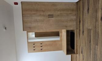 A modern hallway with a wooden coat rack and a cabinet. The walls are bright and the wooden floor feels cozy.