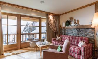 A cozy living room with a red checked sofa and a wood-paneled wardrobe. Large windows offer a view of the snowy landscape outside.