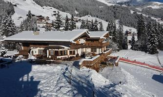 A beautiful chalet in the snowy mountains. Surrounded by snow-covered trees and a clear blue sky.