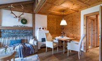 A cozy living area with wooden walls and a dining table. The decor is rustic and inviting, perfect for relaxed moments.