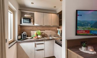 A modern kitchen with wooden cabinets and modern appliances. Fresh vegetables and a plant can be seen on the countertop.