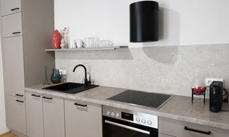 A modern kitchen with clean lines and neutral colors. It includes a stove, a sink, and elegant decorative elements.