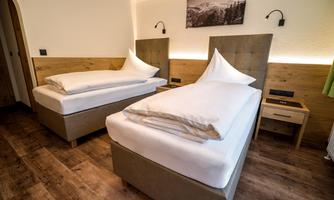 A cozy bedroom with two single beds and modern design. The warm wooden paneling and soft lighting create an inviting atmosphere.