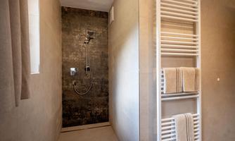 A modern shower with a minimalist design. Towels are neatly placed on a radiator.