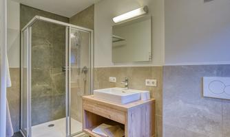 A modern bathroom with a shower cabin and a wooden sink. The walls are in warm tones, creating an inviting atmosphere.