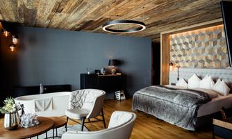 A stylish room with a cozy bed and a freestanding bathtub. The room features modern furnishings and warm wooden details.