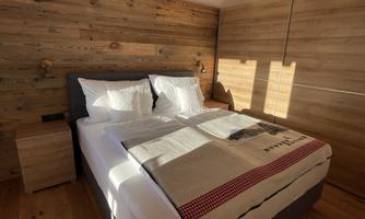 A cozy bedroom with a double bed and wood paneling. The room has plenty of natural light and a modern, rustic design.