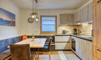 A modern kitchen with a bright dining area. The table is made of wood and the atmosphere is cozy.