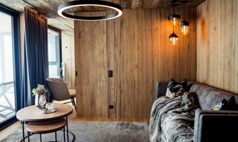 A modern living room with wooden walls and cozy furnishings. There is a couch, a side table, and decorative lighting.