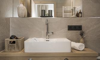 A modern bathroom with an elegant sink and wooden shelves.  
Calm and coziness are conveyed through tasteful decorations and soft colors.