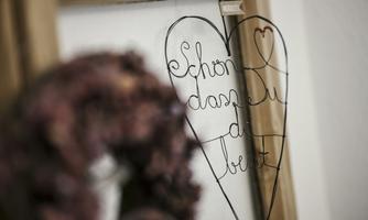 A charming heart made of wire with the inscription "Glad you're here." In the background, a decorative wreath can be seen.