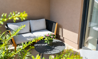 A cozy terrace with a comfortable sofa and a small table.  
Surrounded by plants, it offers a nice place to relax.