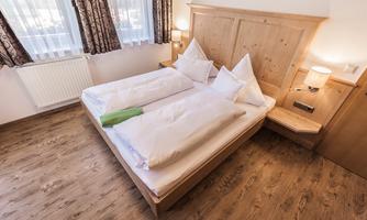 A cozy bedroom with a double bed and light wood design. Bright curtains and a modern atmosphere create a relaxed vibe.