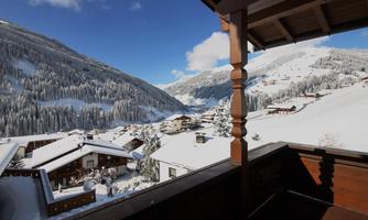 A winter landscape with snow-covered mountains and cottages. The sky is clear and blue, creating a calm atmosphere.