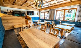 An inviting restaurant with wooden interiors and cozy seating areas. Large windows let in plenty of daylight and create a friendly atmosphere.