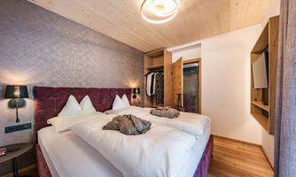 A cozy bedroom with a large double bed and wooden decor. The walls are painted in soft colors, and there is a practical wardrobe.