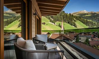A cozy balcony with a view of green hills and picturesque mountains. The surroundings are calm and inviting, perfect for relaxing moments.