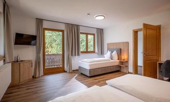 A cozy room with two beds and a large window.  
The room is bright and furnished in a modern style, with wooden flooring and a TV corner.