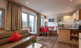 A modern apartment with a cozy living room and an open kitchen. The decor is bright and inviting with wood and fabric elements.