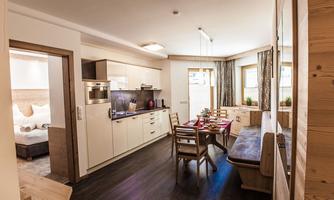 A modern kitchen with wooden elements and a dining area. Light streams through the windows, creating an inviting atmosphere.