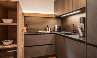 A modern kitchenette with dark cabinets and high-quality materials. The room is well-lit and feels inviting.