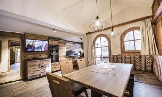 A cozy dining area with wooden furniture and large windows. The room is bright and modernly designed, ideal for social gatherings.