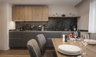 Modern kitchen with an elegant wood front and a stylish marble surface. The dining table is set with dishes and glasses, ready for a cozy meal.