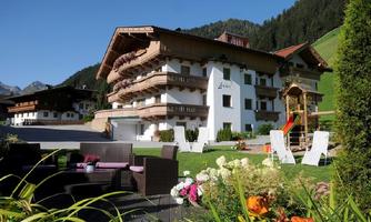 View of the house in summer, Lanhdaus Lexner with hills in the background surrounded by green meadows