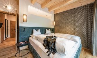 A modern bedroom with two beds and a wooden ceiling. The walls are decorated with an appealing pattern.