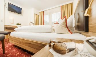 A cozy hotel room with a double bed and modern furnishings. Large windows let in plenty of light, and the room is stylishly decorated.