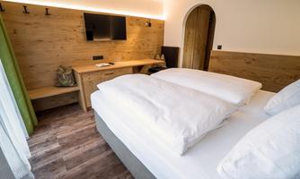 A modern hotel room with a large bed and wooden elements. The room is bright and cozily furnished.